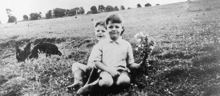 paul mccartney at six-years-old with his older brother sitting on the grass with some chickens