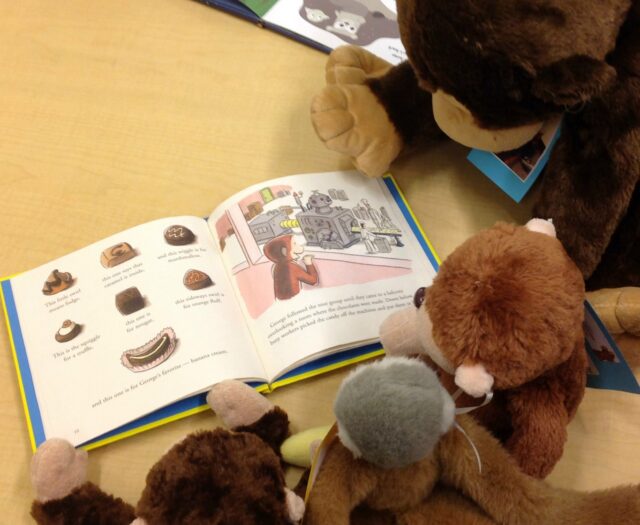 Stuffed monkeys look like they're reading 'Curious George.'