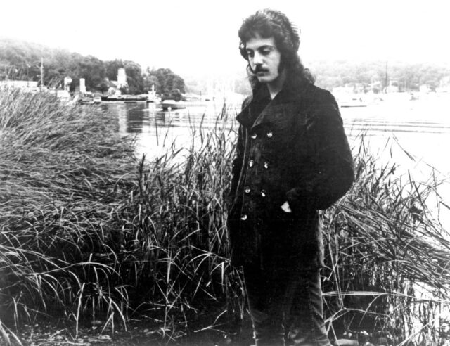 Portrait of Billy Joel standing near a waterway