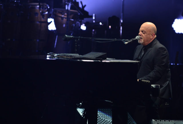 Billy Joel playing the piano on stage