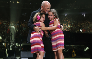 Billy Joel hugging his two daughters on stage