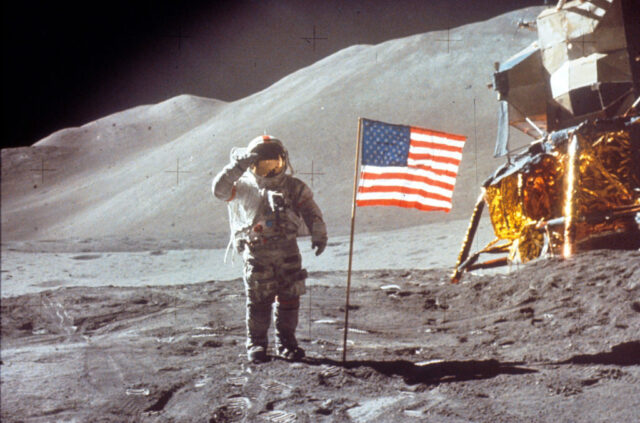 Astronaut saluting beside the American flag on the surface of the moon