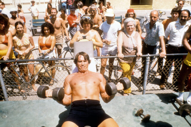 Crowd watching Arnold Schwarzenegger lift weights