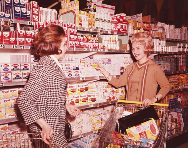 Two women standing in an aisle at a grocery store