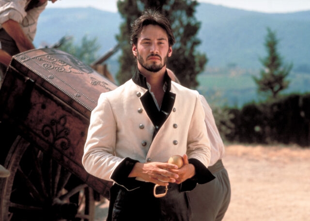 Keanu Reeves as Don John in a white and black historical jacket with two rows of buttons. 