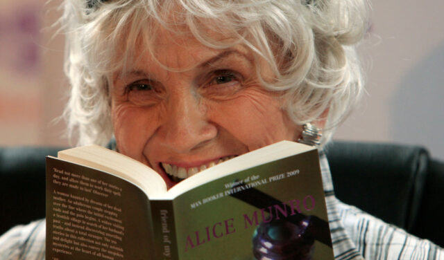 Alice Munro holding an open book up to her face