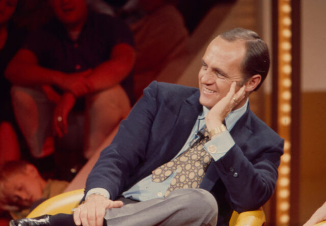 Bob Newhart sitting in a chair on-stage