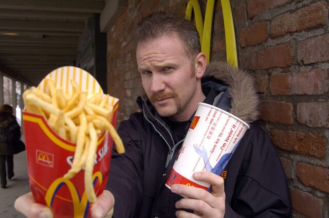 Morgan Spurlock holding a McDonald's drink and fries