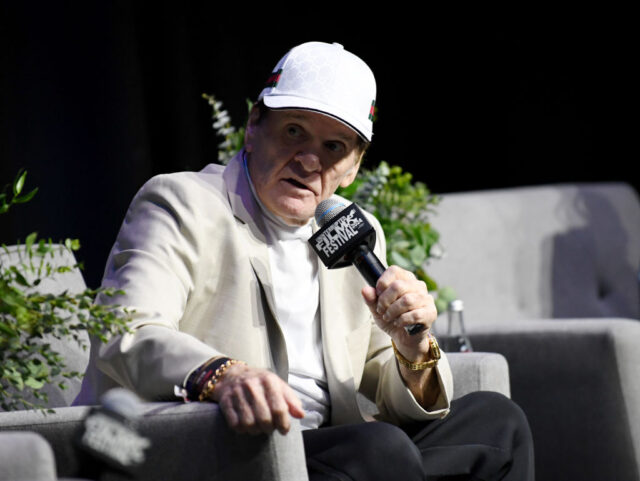 Pete Rose sitting on a stage, holding a mircophone