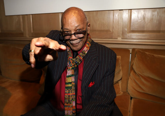 Quincy Jones sitting on a couch, pointing toward the camera