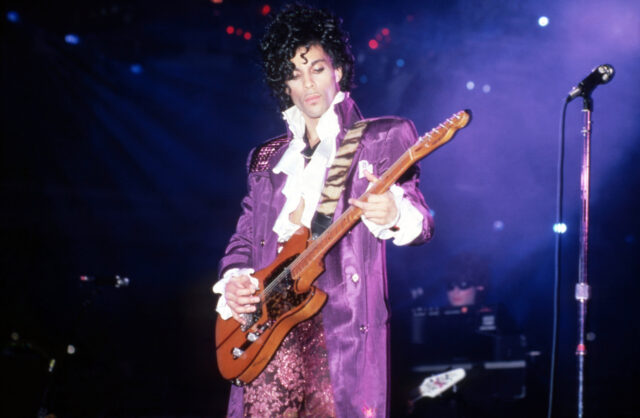 Prince playing the guitar on stage.