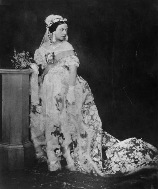 Young Queen Victoria posing for a photo in an ornate gown.