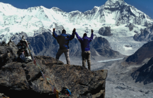 Two hikers holding their hands up on Mount Everest.