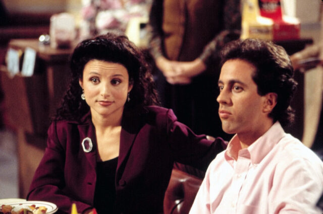 Julia Louis-Dreyfus and Jerry Seinfeld sitting in a booth in 'Seinfeld'
