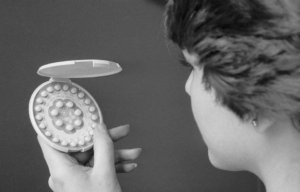 A woman looking at a birth control pack.