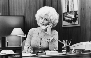 Dolly Parton sitting at a desk on the phone.