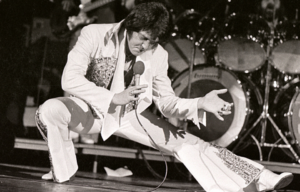 Elvis Presley performing, crouching into a lunge.