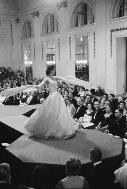 Model twirling on a catwalk while spectators look on