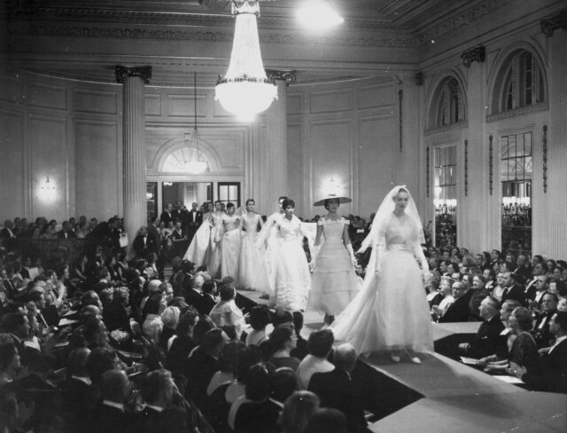 Models walking down a catwalk while spectators look on