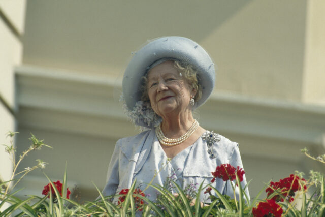 The Queen Mother standing behind some flowers.