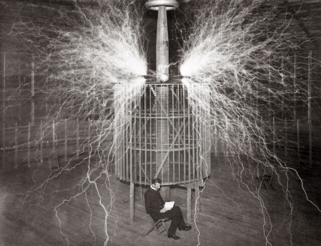 Nikola Tesla sitting beside his "Magnifying transmitter" with electric waves emitting from it.