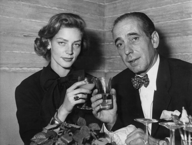 Humphrey Bogart and Lauren Bacall toasting their drinks to the camera.