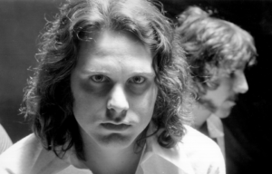 Jim Morrison looking intensely into the camera, someone behind him.