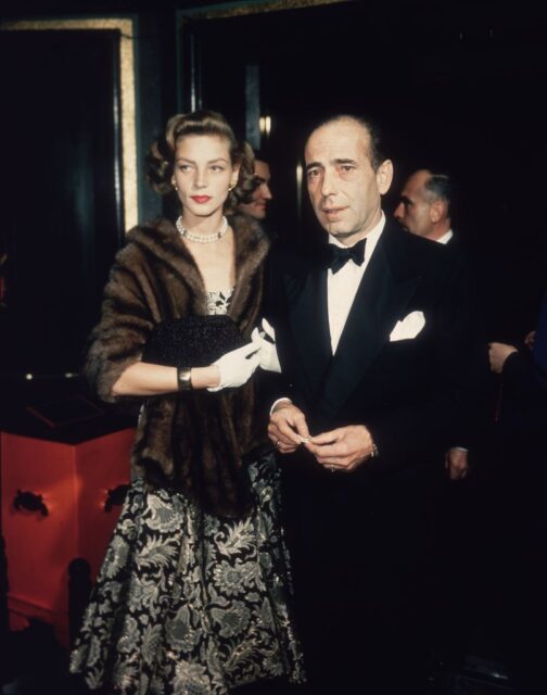 Lauren Bacall and Humphrey Bogart standing together on a red carpet