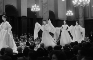 Four models walking down a catwalk as spectators look on