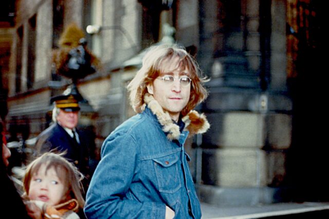 John Lennon walking by, his son Sean visible in the corner of the photo.