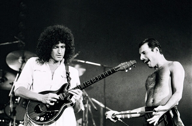 Brian May and Freddie Mercury playing on stage.