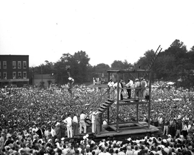 A crowd of people gathered around a public hanging device.