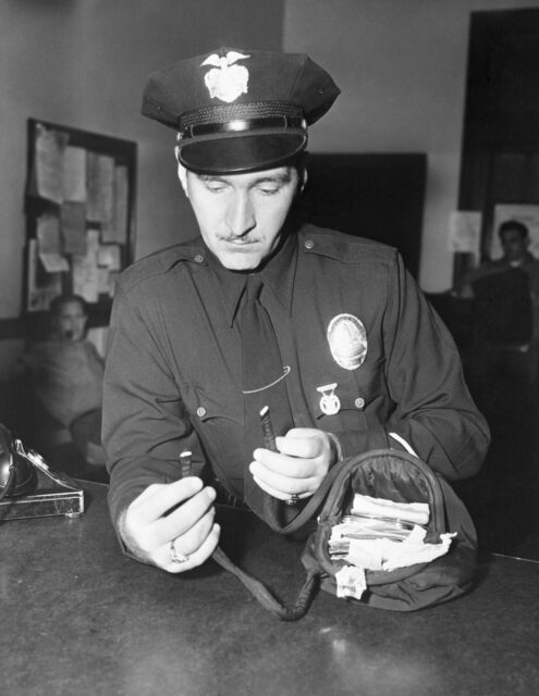 Howard Rose examining Jean Spangler's purse at a desk