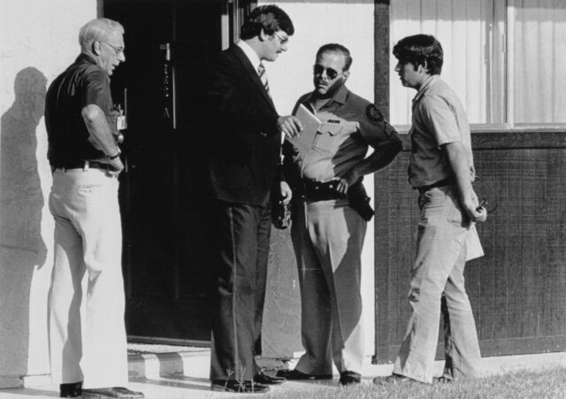 Four men standing outside of an apartment door.