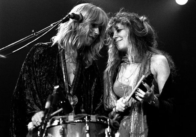 Stevie Nicks and Christine McVie playing instruments, their foreheads touching.