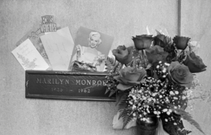 The name plate of Marilyn Monroe's grave, flowers and photos upon it.