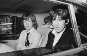 Mick Jagger and Keith Richards sitting in the back seat of a car.