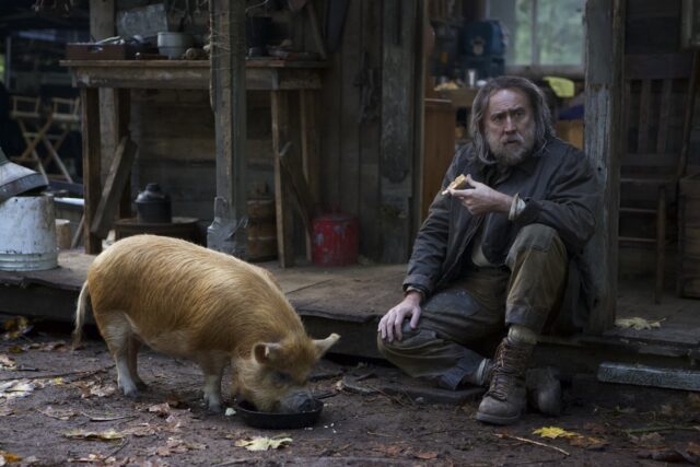 Nicholas Cage beside a hairy pig.