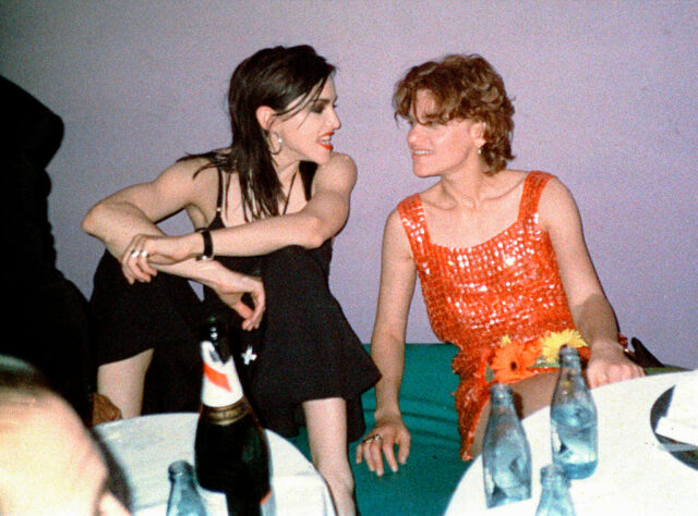 Madonna and Sandra Bernhard sitting together on the ground