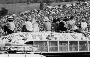 People sitting atop a hippy bus at Woodstock music festival.