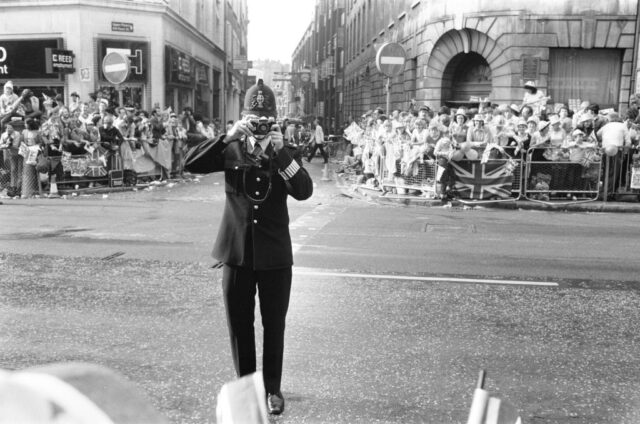 Police officer standing in the middle of a street, holding a camera