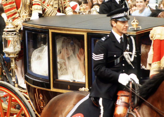 Lady Diana Spencer waving to a crowd of people from within a horse-drawn carriage