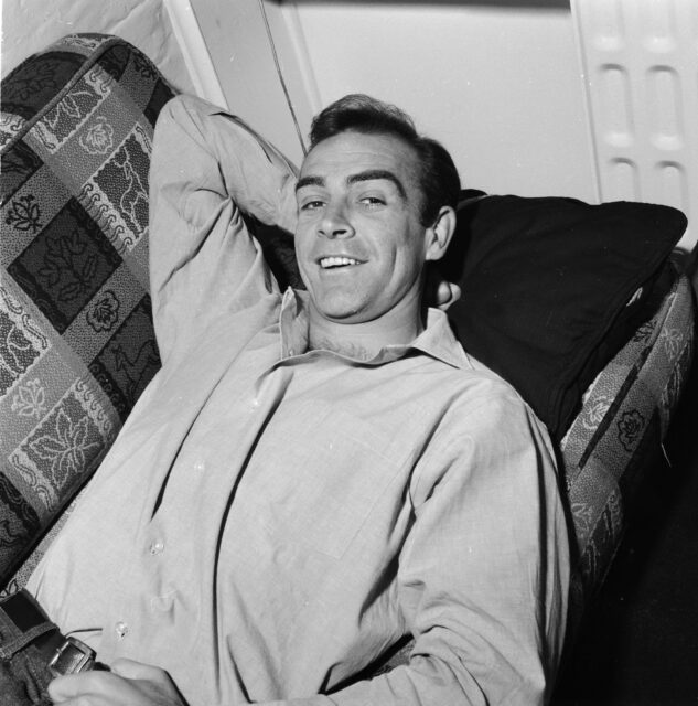 Sean Connery laying on a couch, one hand behind his head.