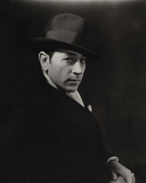 George Raft looking from the side with a hat on.