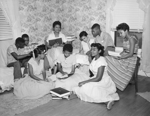 A group of nine teenagers sitting in a living room.