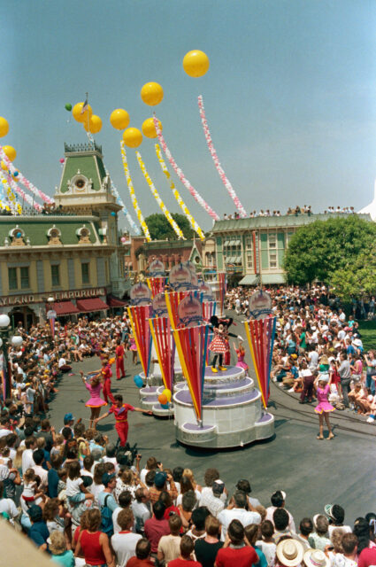 Crowds watching a parade move along a road in Disneyland