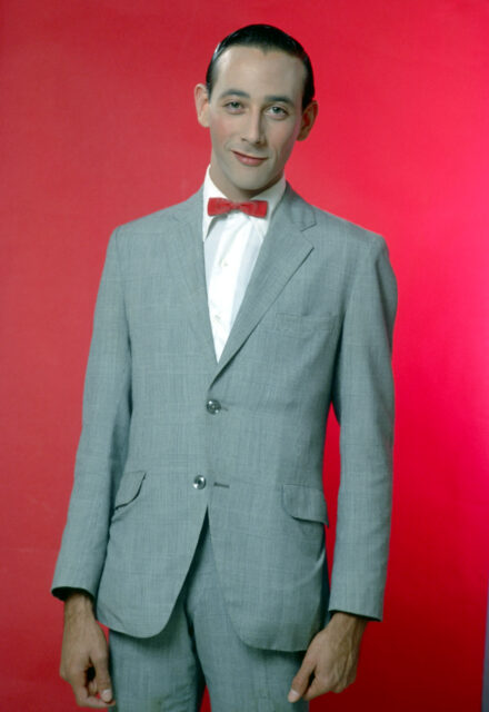 Pee-wee Herman standing in a suit/