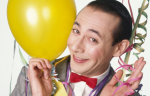 Pee-wee Herman holding a balloon and streamers.