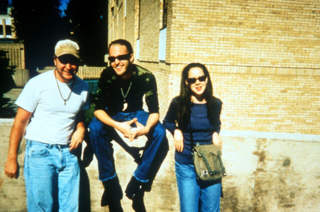 Michael C. Williams, Joshua Leonard, and Heather Donahue, sitting on a wall. 