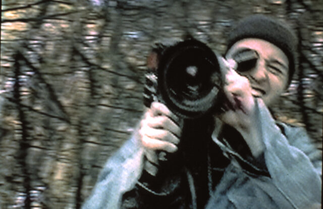 Photograph of a man holding a large video camera.